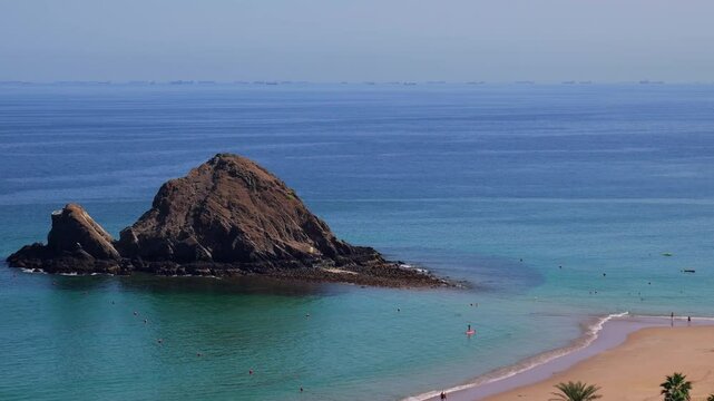 Snoopy Island in Fujairah, UAE. Aerial view of the beach with turquoise waters, a rocky island and a resort nearby