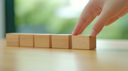 Hand Placing Wooden Blocks on Table in Bright Natural Light Environment