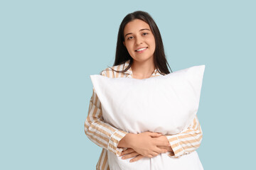 Fototapeta premium Smiling young woman in striped pajamas cuddling soft white pillow, comfort and relaxation concept, sense of peaceful wellbeing and a cozy home lifestyle