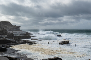 Massive waves crash against the beach, creating a dramatic and powerful scene during a fierce storm