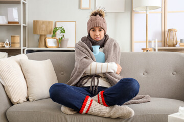 Obraz premium Sick young woman with hot water bag at home