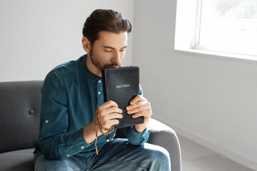 Man with Bible sitting on sofa  at home