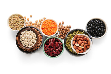 Composition with bowls of different raw legumes on white background