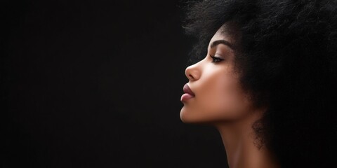 Fototapeta premium Profile of a stunning young model showcasing her beauty against a sleek black background, highlighting her elegant afro hairstyle and striking features