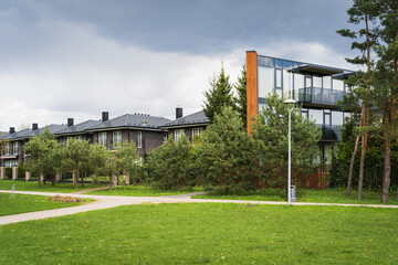 Naklejka premium Modern residential complex with townhouses and an apartment building in a green suburb.