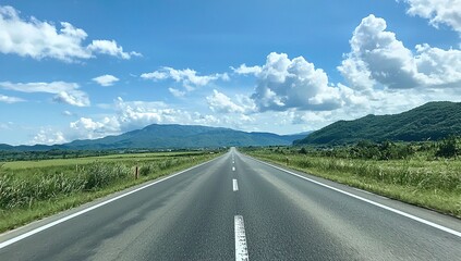 Empty Road Leading Towards Mountains Under Blue Sky With Clouds
