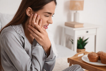 Young woman suffering from toothache in bedroom, closeup