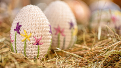 A set of crochet eggs with intricate flower designs is arranged delicately in a natural straw setting, embodying the charm of handcrafted art.
