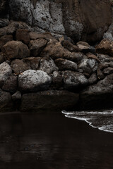 black sand beaches with white frothy waves and dark rocks