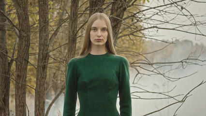 Fashion model posing in green dress by foggy lake