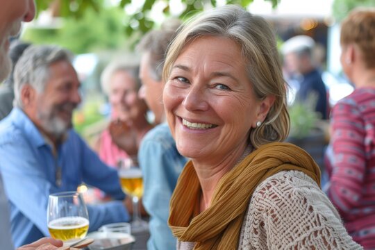 Portrait of smiling senior woman sitting at table in cafe and drinking beer