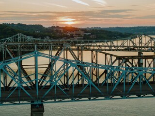 Vibrant sunset over a city skyline, with a blue bridge carrying traffic across the river. Urban landscape at dusk. Clay Wade Bailey Bridge, Cincinnati, Ohio, United States