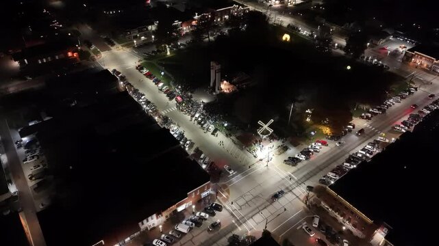 IOWA - 12.6.2024 - Fantastic aerial view beginning to circle a park lit up at night for a Christmas festival in Pella, Iowa.