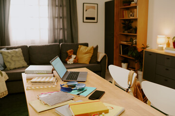 No people shot of modern living room interior with students textbooks, notebooks, gadgets and laptop on wooden table