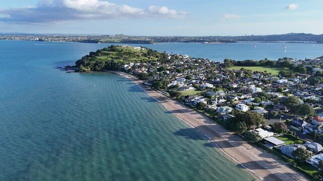 Aerial drone footage of Cheltenham Beach, Devonport, New Zealand, showcasing golden sands, turquoise waters, lush greenery, and stunning views of North Head.