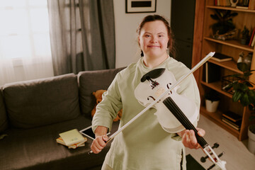 High angle view medium shot of cheerful young woman with Down syndrome smiling at camera while...
