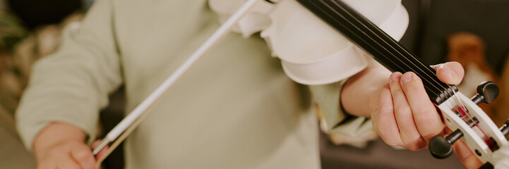 Medium closeup of unrecognizable girl with Down syndrome practicing violin, header for website