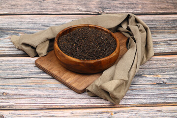 Dry black tea leaves isolated on wooden background, top view