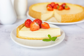 Classic sliced homemade New York cheesecake with fresh strawberries served on a marble countertop. Homemade dessert.  