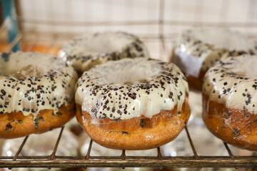 A row of donuts with a white frosting and black sprinkles, Easter baking at the factory