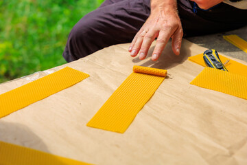A man rolls decorative candle made of natural beeswax