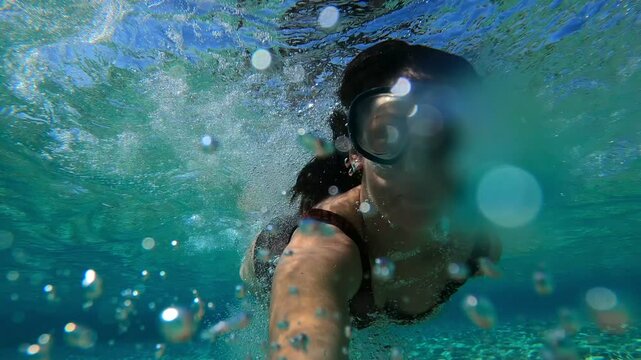 Woman diving and looking underwater view in turquoise water of Simos beach in Elafonisos island in slow motion, in Greece