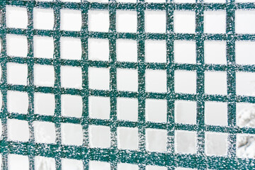 Snow-covered green mesh fence in winter landscape