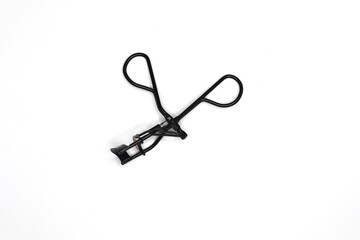 A black eyelash curler is isolated on a white background.