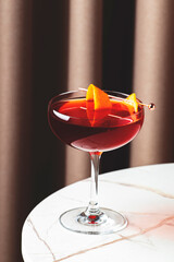 Revolver, alcoholic cocktail drink with bourbon, coffee liqueur, orange bitter and peel. Marble table with fabric curtain background, lifestyle