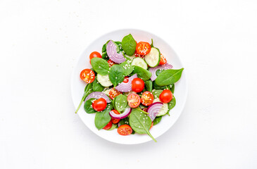 Spring healthy vegetable salad with spinach, tomatoes, cucumber, red onion and olive oil. White background, top view