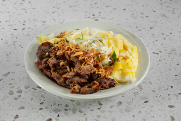 A view of a Vietnamese entree, featuring rice rolls and grilled pork.