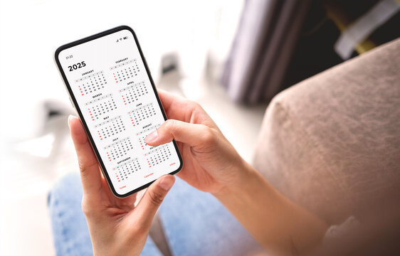 Businesswoman using smartphone with monthly calendar to plan 2025 activities. Scheduling and organizing plans. Technology and business concept.