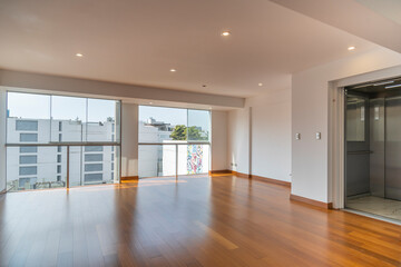 Vista de sala de departamento con amplia mampara con vista a la calle , con acabados modernosm, piso de madera y paredes blancas 