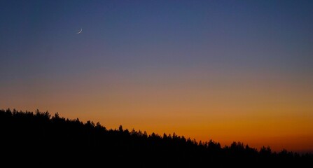 sunset in the mountains with moon in the sky