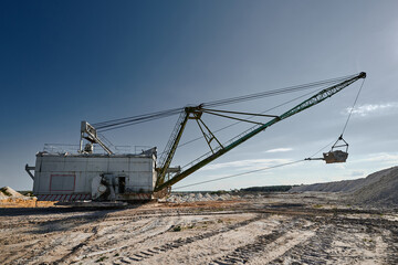 Walking excavator mines chalk in large pit on sunny day