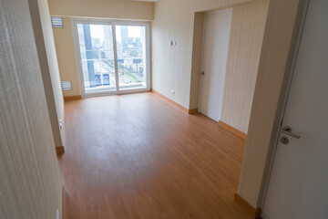 Vista de sala de departamento con amplia mampara con vista a la calle , con acabados modernosm, piso de madera y paredes blancas 