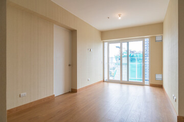 Vista de sala de departamento con amplia mampara con vista a la calle , con acabados modernosm, piso de madera y paredes blancas 