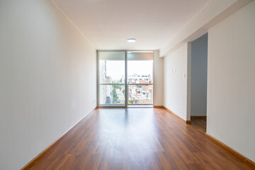 Vista de sala de departamento con amplia mampara con vista a la calle , con acabados modernosm, piso de madera y paredes blancas 
