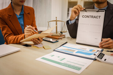 Two male and female lawyers sit at a table in an office, discussing legal matters related to...