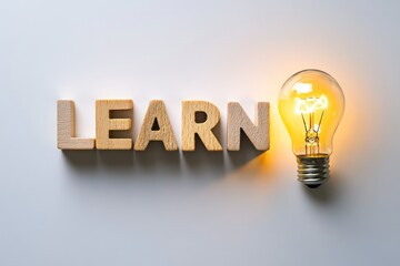 The word "LEARN" made of wooden cubes placed on a white surface, a light bulb glowing brightly next to it, leaving space for a motivational quote.