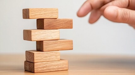 Delicate Balance of Wooden Blocks with Hand About to Create Collapse