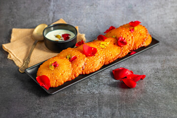 Malpua is a traditional Indian sweet, consisting of deep-fried pancakes made from flour, sugar, and coconut, often flavored with cardamom, served with syrup or milk.