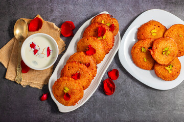 Malpua is a traditional Indian sweet, consisting of deep-fried pancakes made from flour, sugar, and coconut, often flavored with cardamom, served with syrup or milk.