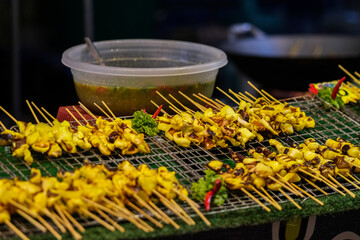 Grilled squid skewers on display at a vibrant Thai market.