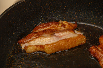 Sizzling pork belly being perfectly cooked in a hot skillet