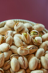 Pistachios in a green cup on a burgundy backgroundVegetarian plant-based protein source. Healthy snack. Healthy nutrition.