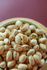 Pistachios cup on a burgundy background.Healthy fats.Vegetarian plant-based protein source. Healthy snack. Healthy nutrition.Vegetarian and vegan food