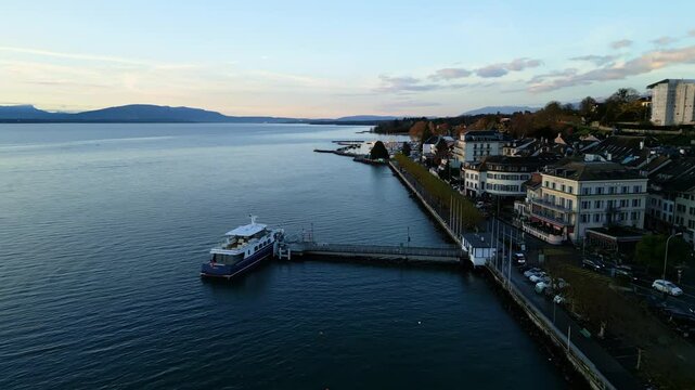 Pull out drone shot of boat at Nyon port at sunrise on Lake Geneva in Canton of Vaud Switzerland