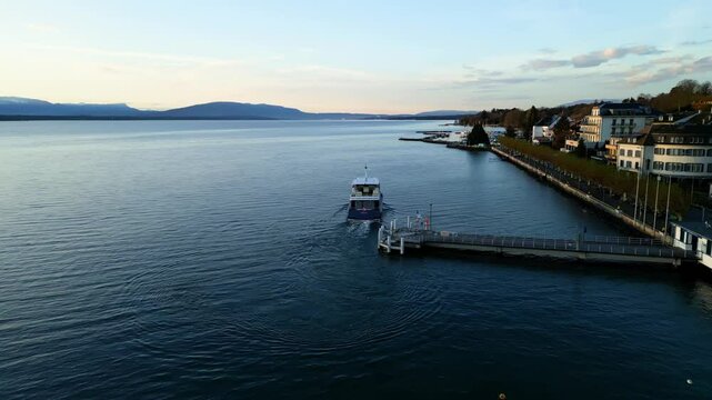 Push in drone shot of boat leaving Nyon port at sunrise on Lake Geneva in Canton of Vaud Switzerland