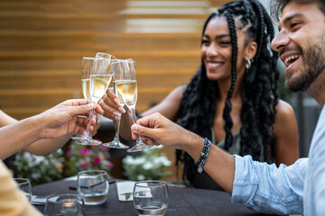 Cheerful friends toasting with champagne glasses at outdoor dinner